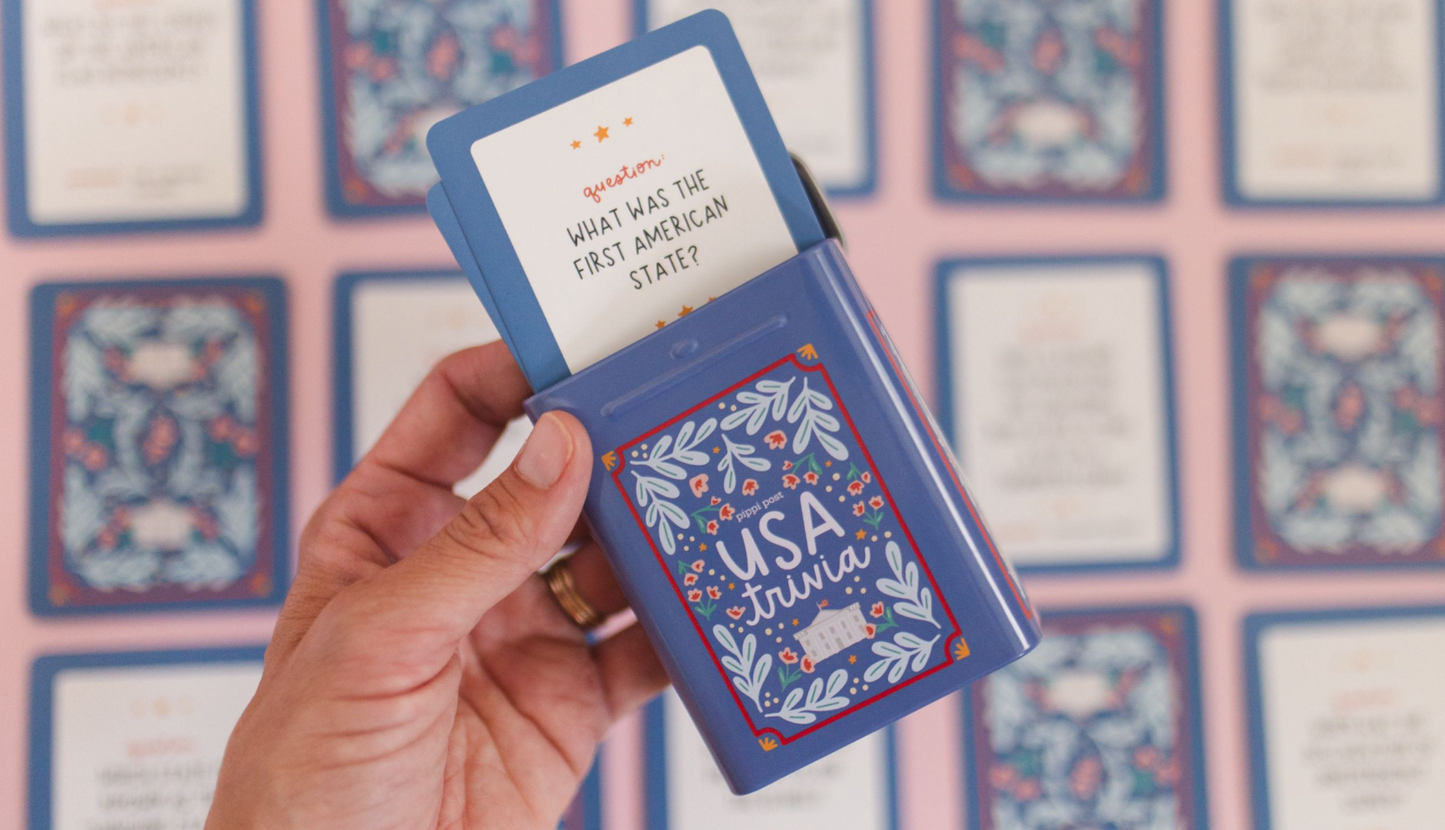 Hand holding a blue card with 'USA trivia' text against a patterned background