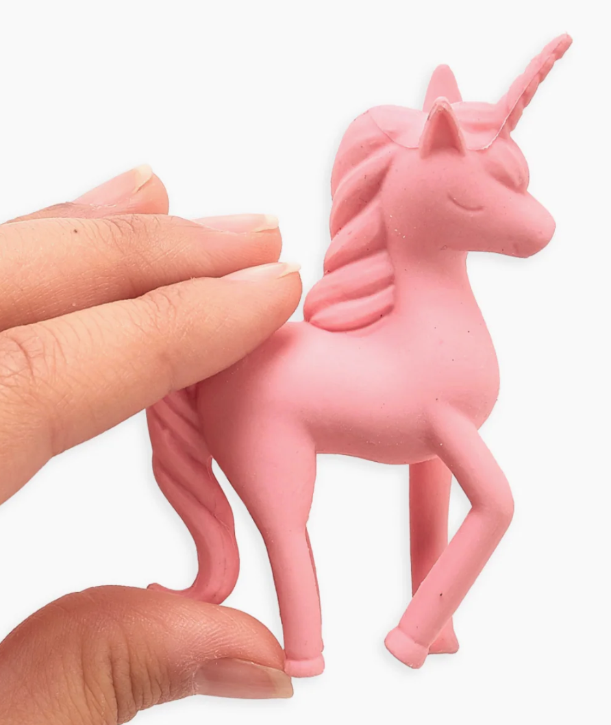 Pink unicorn figurine held by a hand on a white background