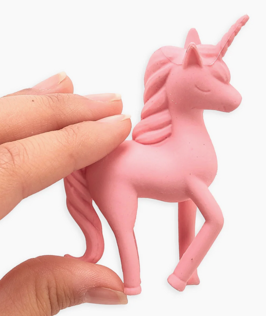 Pink unicorn figurine held by a hand on a white background
