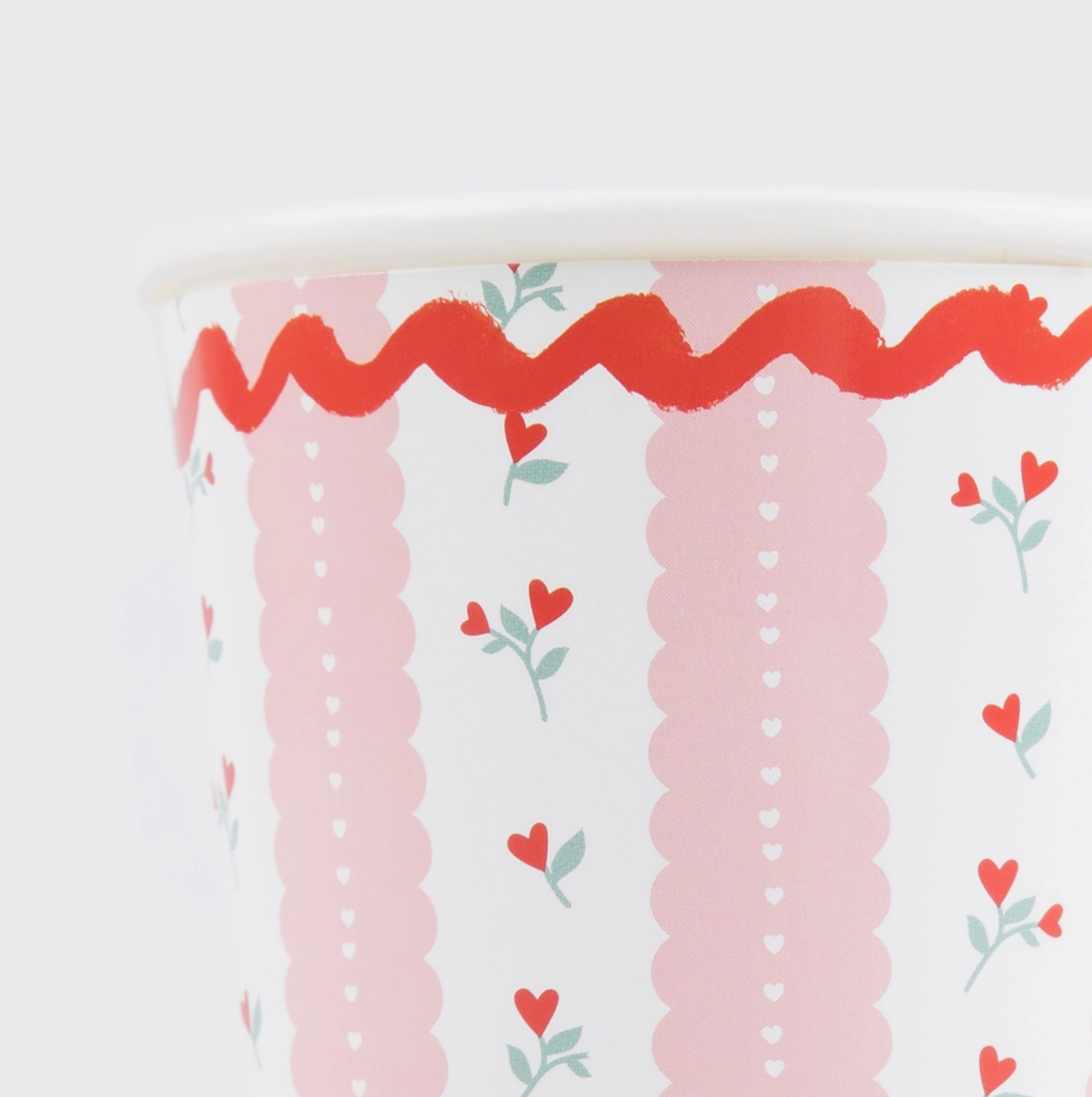 Decorative paper with pink scalloped edge and red heart designs on a white background