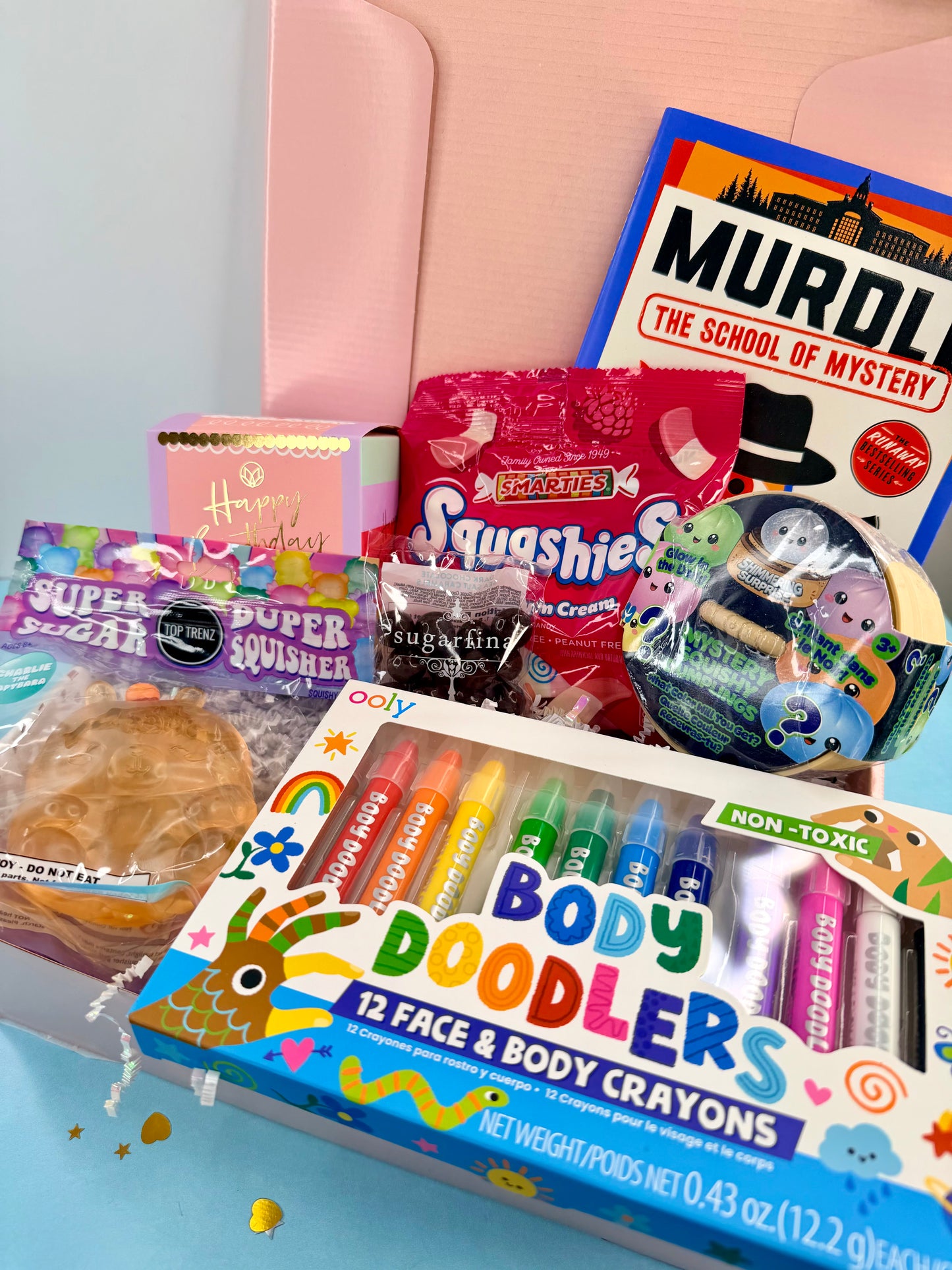Assorted children's toys and snacks on a pink couch with a 'Murdo' book in the background.