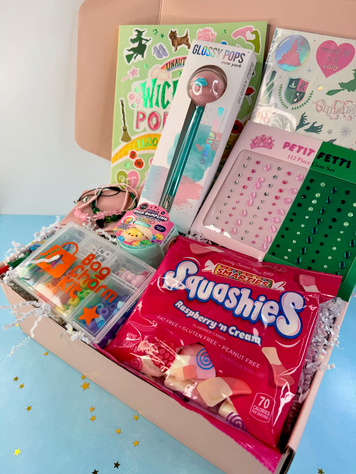 Open pink Wicked-themed gift box for tweens with themed surprises arranged inside.