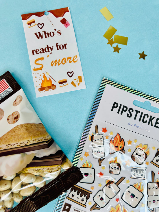 S'mores-themed items including a card, stickers, and marshmallow treats on a blue background.