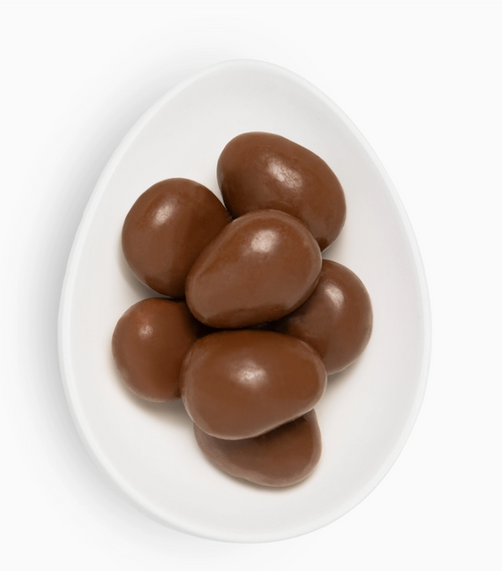 Chocolate-covered almonds on a white plate with a white background