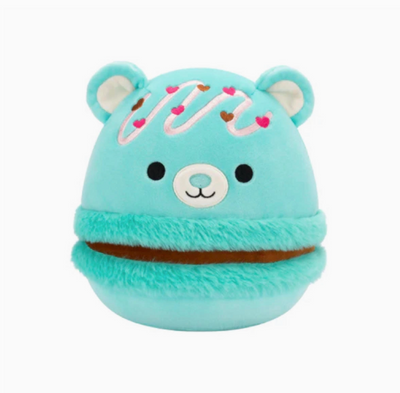 A blue Squishmallow plush toy resembling a bear with a marshmallow-like texture, featuring heart decorations and a pom-pom.