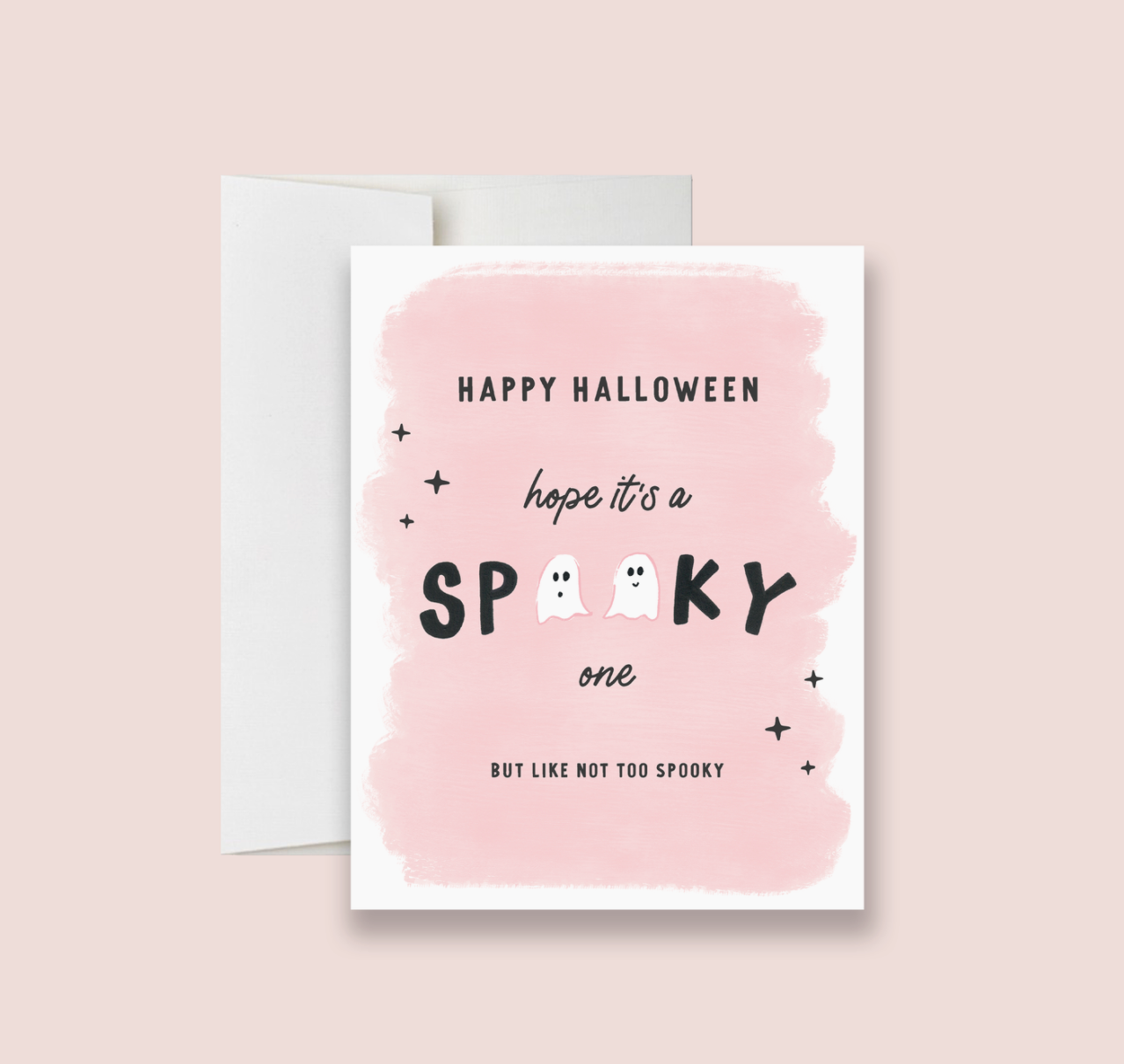 A folded Halloween greeting card with a pink background, text 'Happy Halloween' and 'I hope it's a spooky one BUT NOT TOO SPOOKY', and decorative elements like stars and a ghost. The card also includes a white envelope.